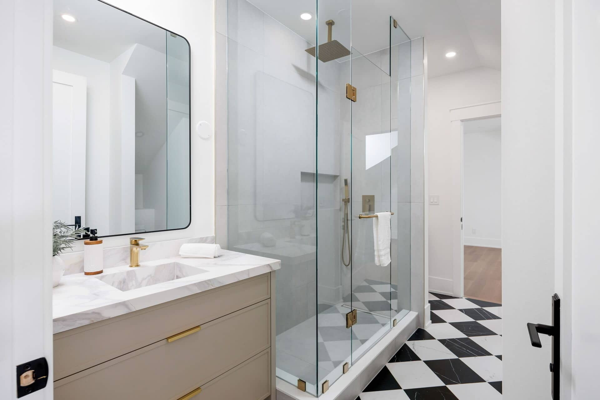 Ensuite with a taupe vanity, marble top and brass tap, a frameless glass shower and a chequerboard marble floor