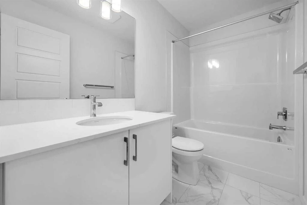 Compact condo bathroom with a white gloss vanity, tub and shower surround, and marble look floor tile